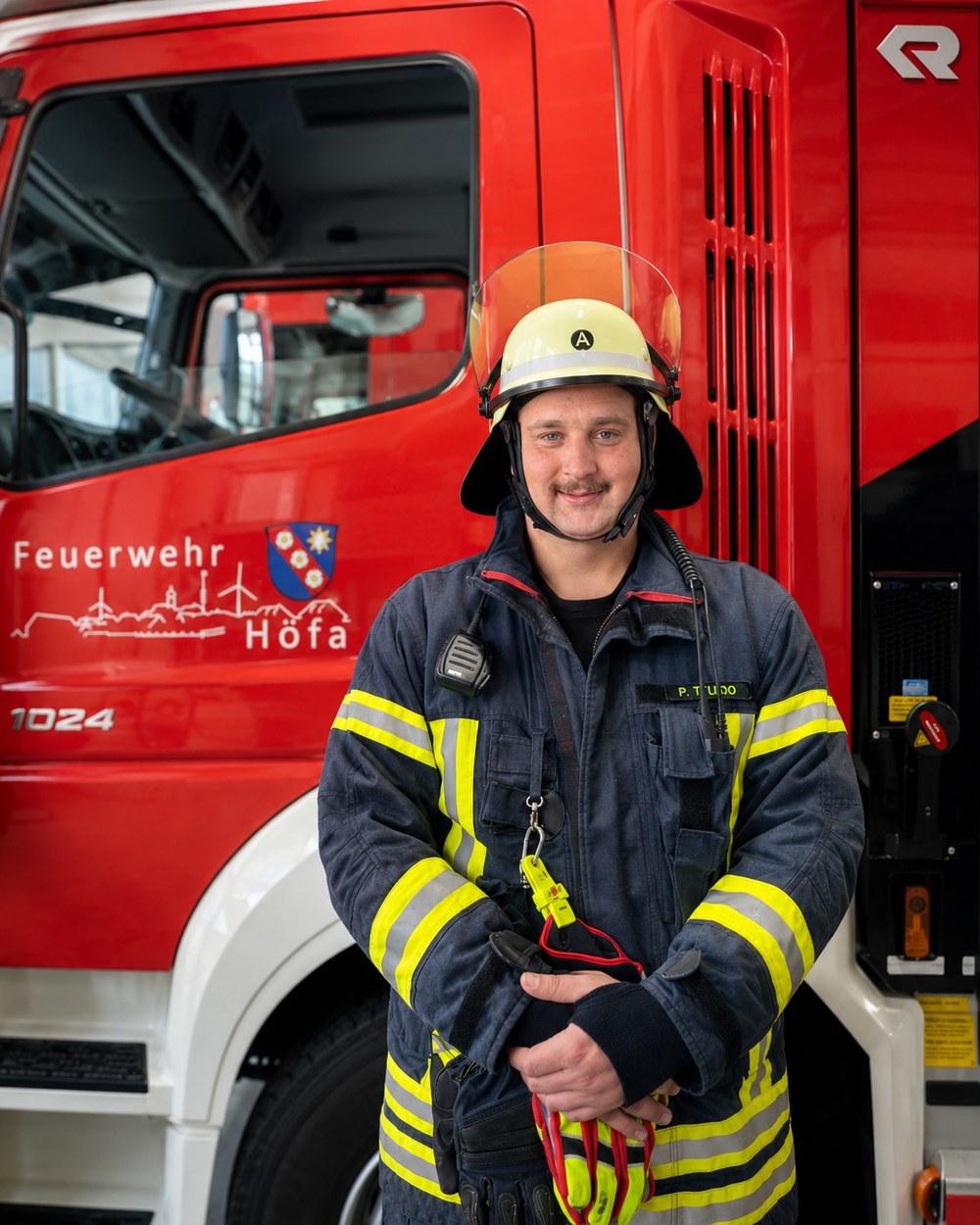Patrick Piza de Toledo in Feuerwehrschutzkleidung vor einem Einsatzfahrzeug der Feuerwehr Höfa